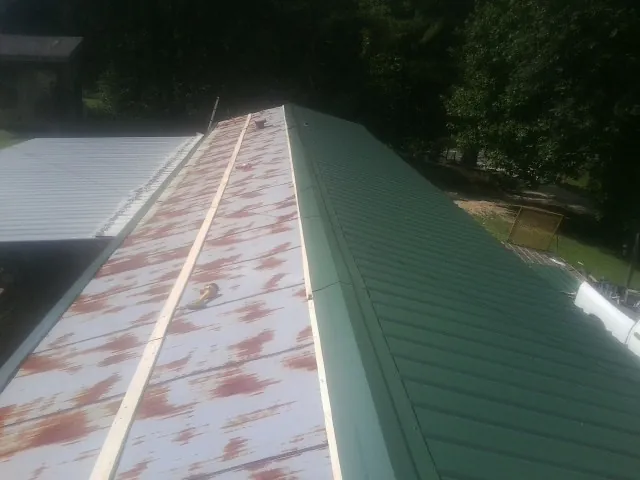 Old rusted panels beside newly installed green metal roofing — Wind Damage Roof Repair by Roofing Brothers in Carmel Valley