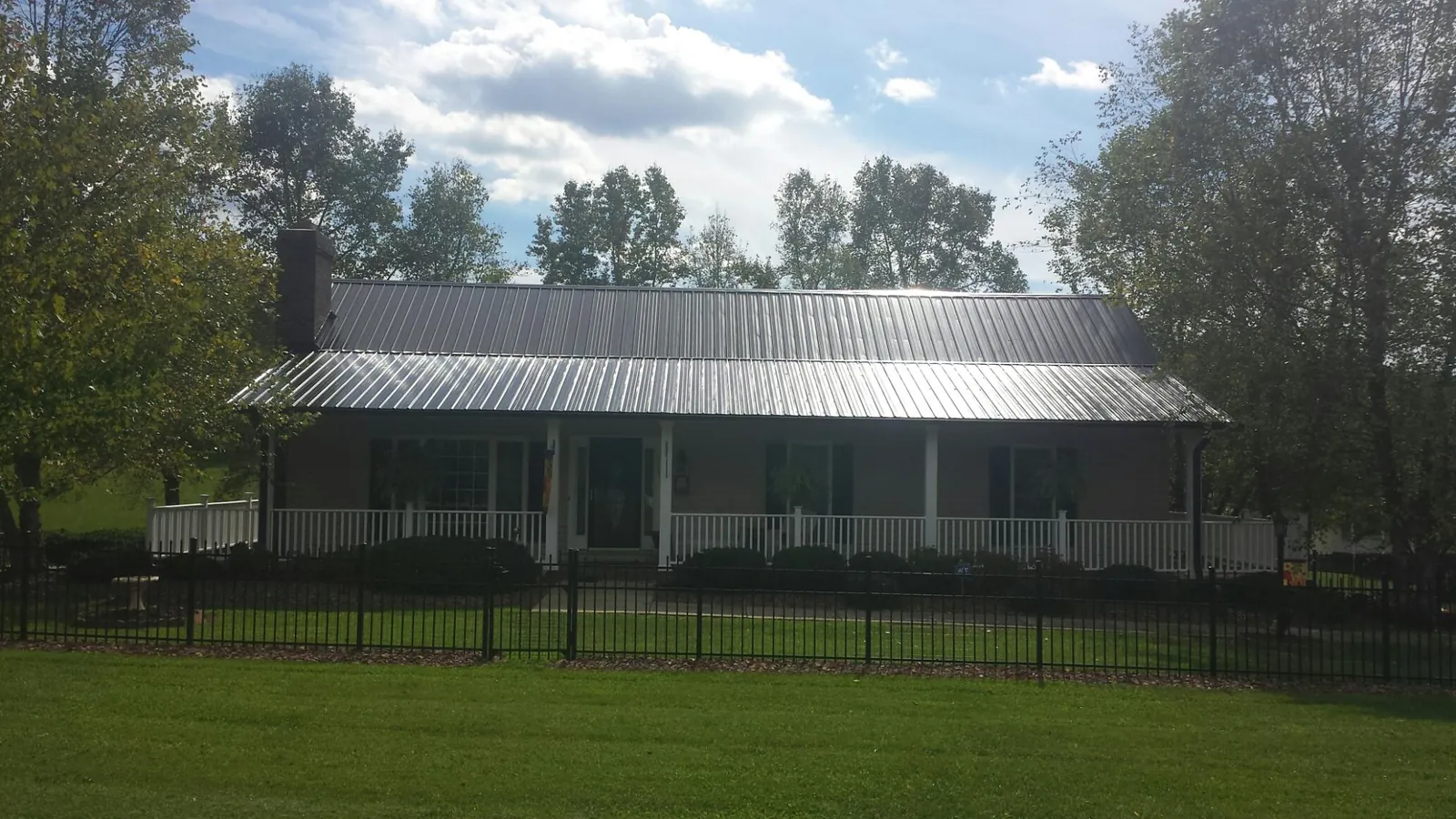 Gray metal roof on a brick ranch with a full width front porch — Gutter Guard Installation work by our crew in Carmel Valley