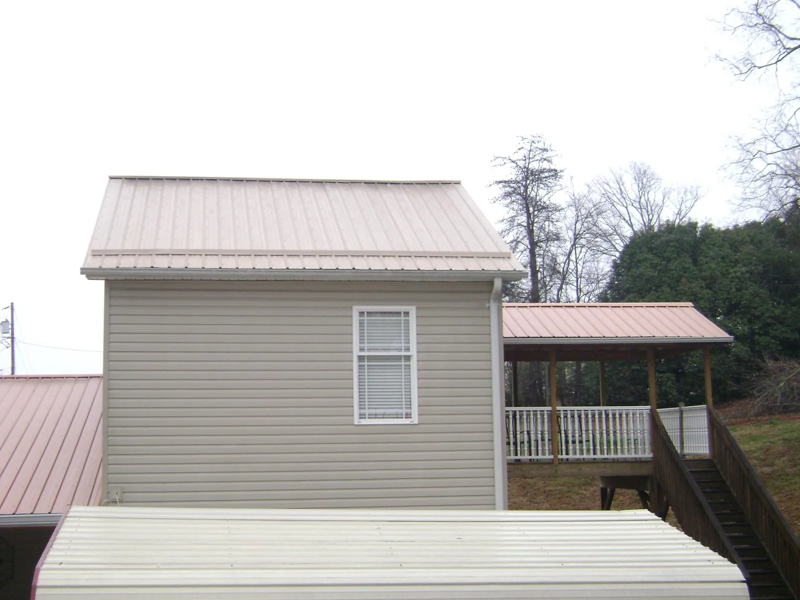 Tan metal roofs on a two story addition and attached porch, from a Roof Replacement job in Carmel Valley