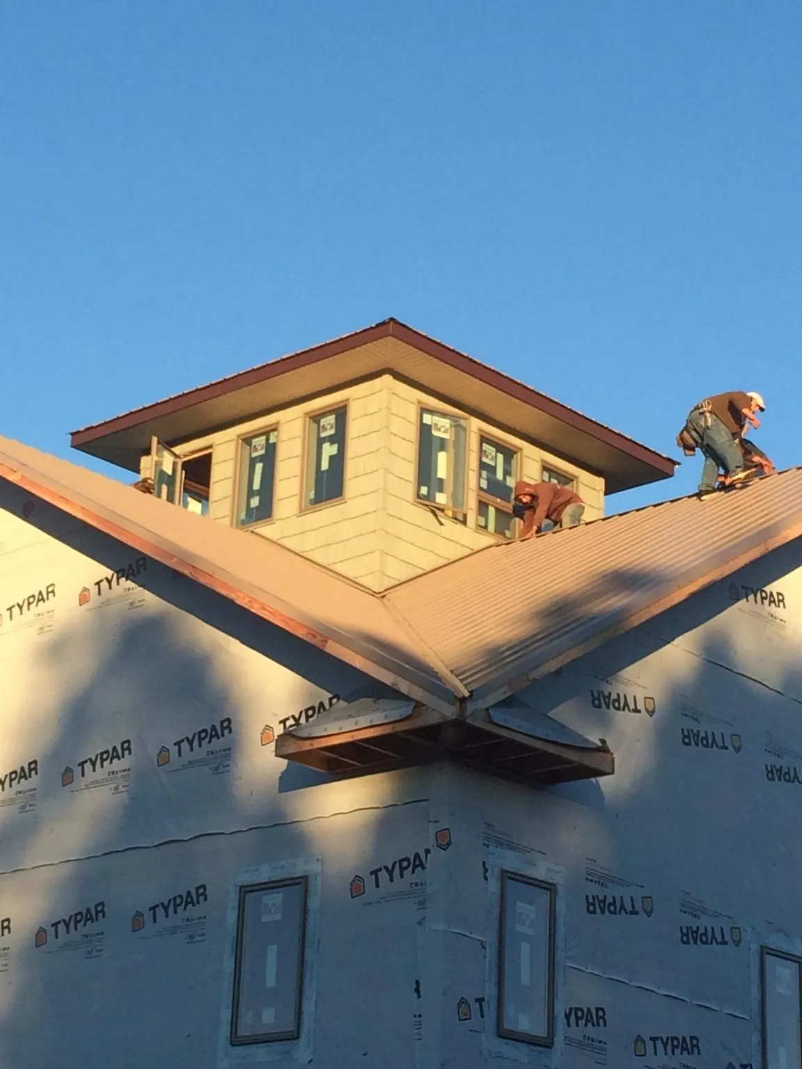 Roofers working around a rooftop cupola on a new metal roof at sunset — Roof Waterproofing in Carmel Valley by Roofing Brothers